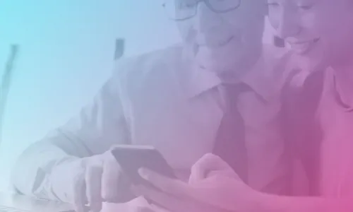 Image of an older man looking at a phone with a younger woman. There is a laptop open in front of them.