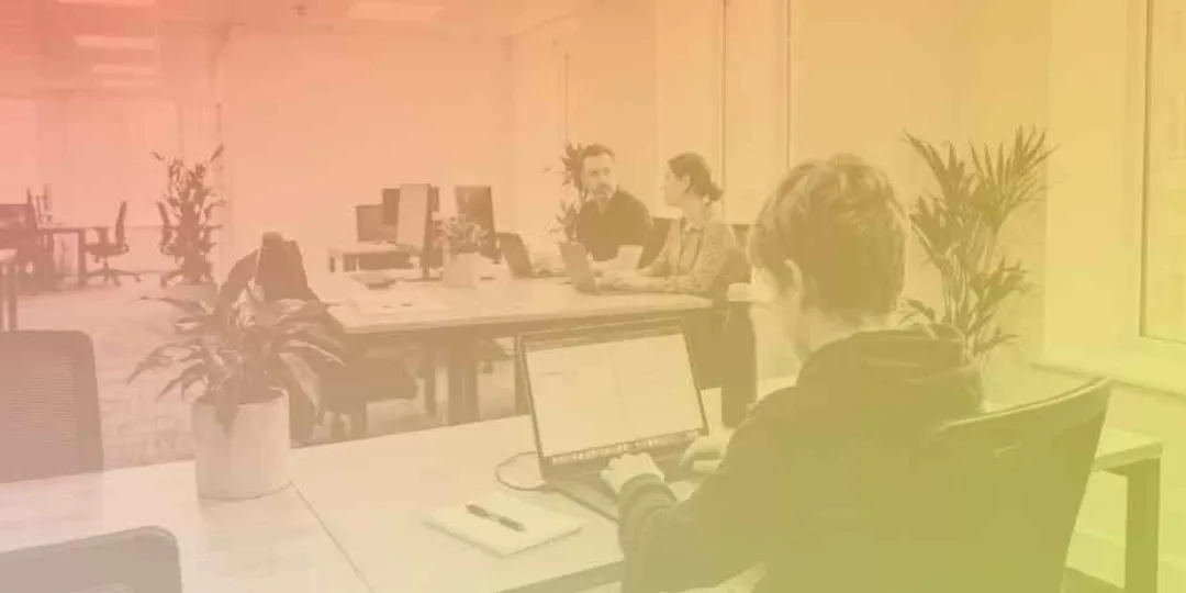 Image of a student working a laptop in an office