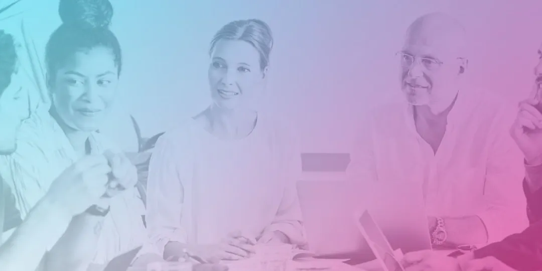 A team of well dressed, happy people sitting around a desk having a meeting