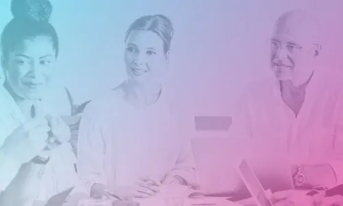 A team of well dressed, happy people sitting around a desk having a meeting