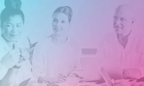 A team of well dressed, happy people sitting around a desk having a meeting