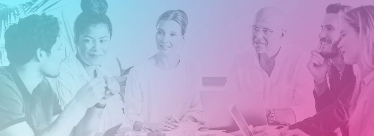A team of well dressed, happy people sitting around a desk having a meeting